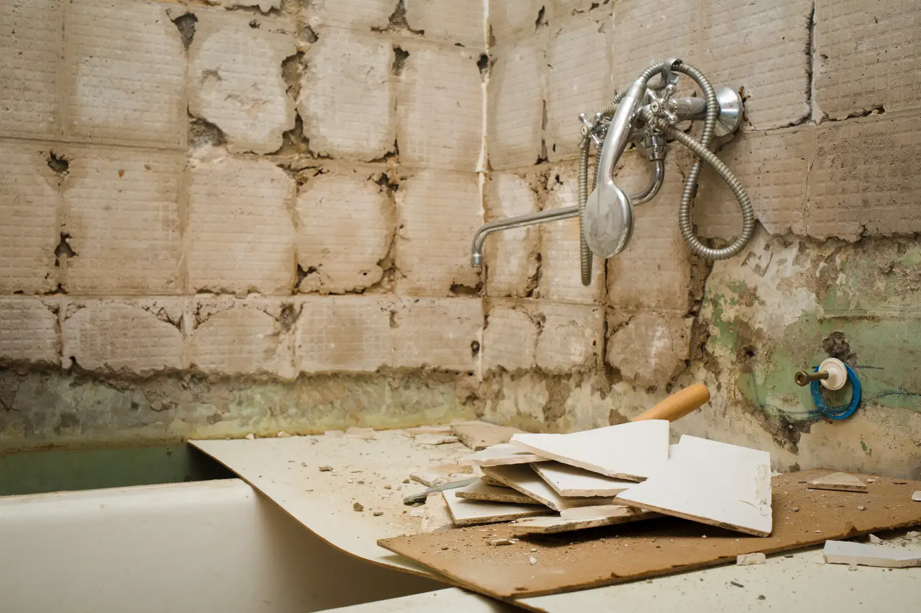 Cracked grout and loose tile in a bathroom wall